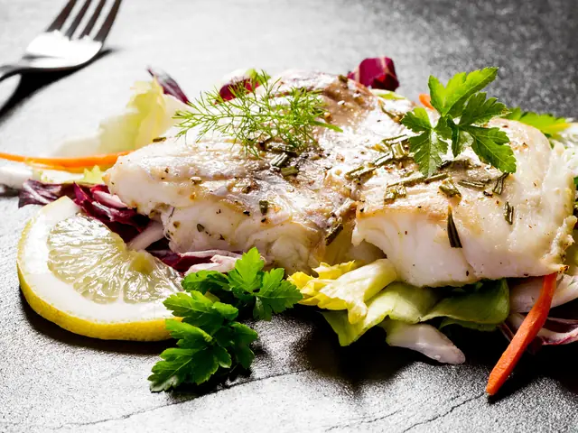 File de pește alb copt, cu rozmarin, mărar și pătrunjel, pe salată cu radicchio, lângă o felie de lămâie