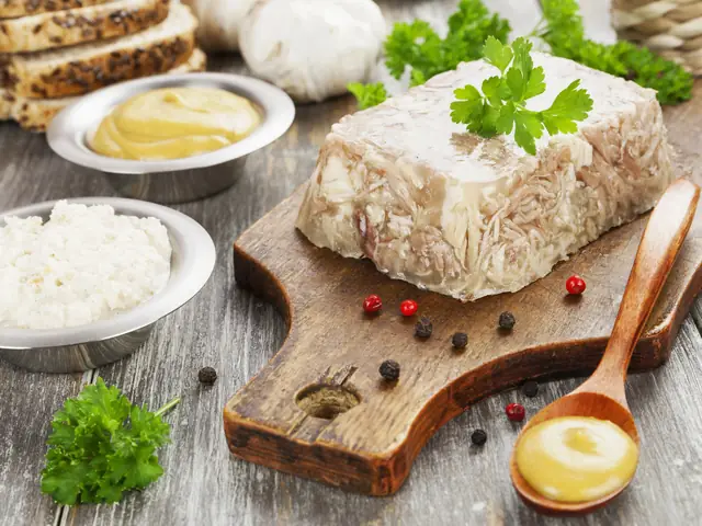 Piftie de porc închegată, întoarsă pe un fund de lemn, cu pătrunjel, boabe de piper, muștar și hrean alături
